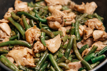Stewed beans with chicken meat in soy sauce in a frying pan