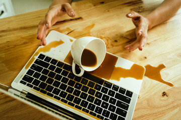 Morning mishap: hot coffee spills over office laptop and documents on a desk, causing wet stains, electronic hazard, and frustration.