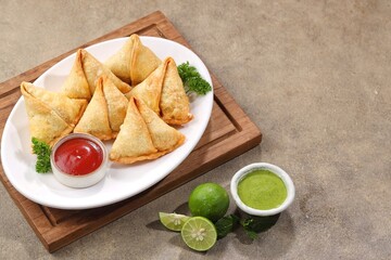 Samosa or samboosa is a triangular fried pastry filled with boiled potatoes seasoned with spices mixed with peas, onions, coriander leaves, and sometimes paneer.