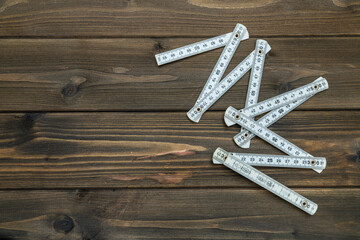 A folding ruler lying on an old wooden table of dark brown color.