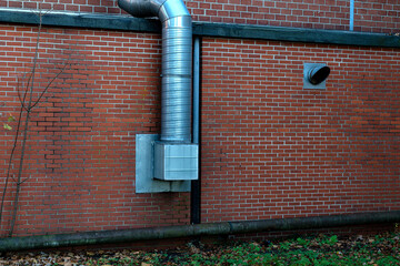 Metal ventilation system attached to a brick wall in a building