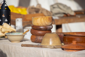 Assortment of rustic handmade bowls, cups, and jugs in a wicker basket on display at traditional outdoor market stall