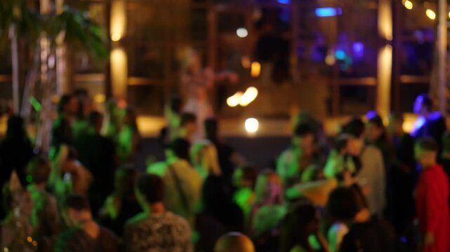 Defocused shot, tourists enjoy performance, with crowded dance floor and vibrant nightlife scene. Entertainment, music, and relaxation define this famous island destination, attracting young people