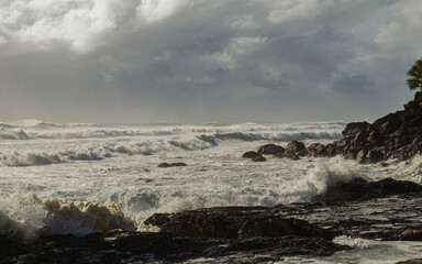 Rough storm surf generated by an approaching cyclone rolls in towards the rocky shore under...
