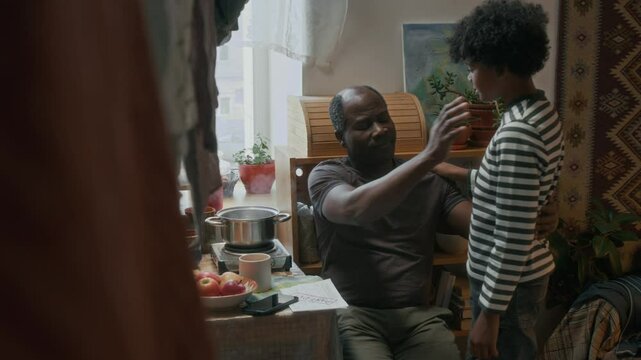 Poor African American man sitting in kitchen and stressing about his past due bills, hugging and supporting his son