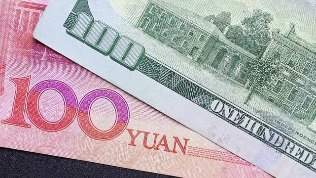Close up view of rotating Chinese Yuan (CNY) and American Dollar (USD) banknotes. Concept of  international trade restrictions, tariff wars for economic dominance, USA and China reciprocal sanctions.
