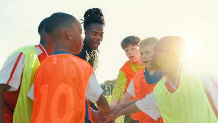 Hands together, soccer and coach in huddle with children on field for motivation, game plan and...