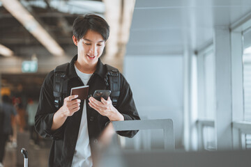 Happy traveling asian man uses mobile smartphone hold passport, checking trip destination on...