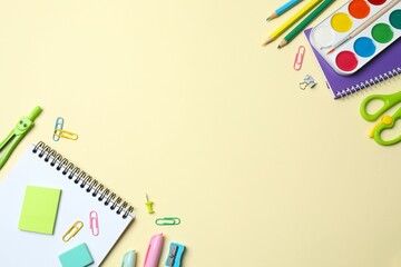 School supplies creatively arranged on a color surface, including notebook, paints, stationery