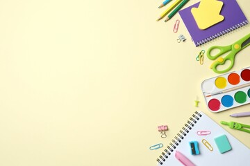 A collection of school supplies including pencils, notebooks and paints on a coloured background, ideal for school holidays or an educational context. Top view