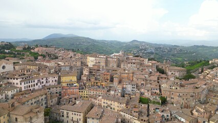 Fototapeta premium Drone aerial view of the historic center of Perugia with the houses perched on the hills of the Umbrian Apennines with the houses with the typical tiled roofs matching each other - Piazza IV Novembre