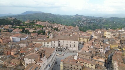 Fototapeta premium Drone aerial view of the historic center of Perugia with the houses perched on the hills of the Umbrian Apennines with the houses with the typical tiled roofs matching each other - Piazza IV Novembre