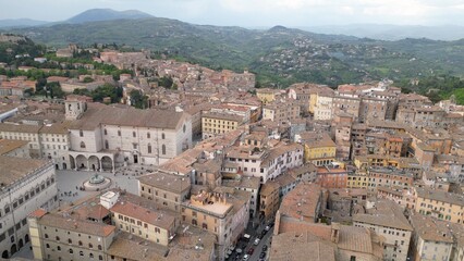 Drone aerial view  of the historic center of Perugia with the houses perched on the hills of the Umbrian Apennines with the houses with the typical tiled roofs matching each other - Piazza IV Novembre