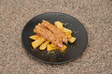A plate of meat and potatoes. The meat is cut into small pieces and is served with potatoes