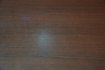 Naklejka premium A wooden surface with a light shining on it. The light is reflected on the wood. The wood is brown in color