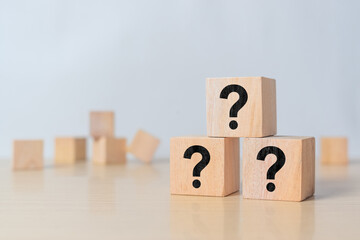 Wooden blocks showing three question marks representing inquiry, doubt, and knowledge seeking....