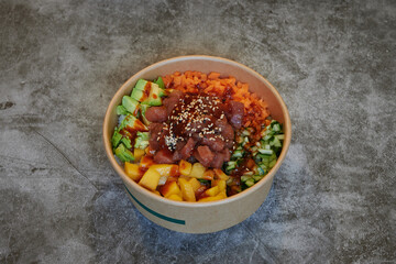 A bowl of food with a variety of ingredients including carrots, avocado, and seaweed. The bowl is made of paper and is placed on a counter
