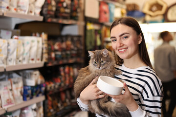 Woman with her cute cat and feeding bowl in pet shop. Space for text