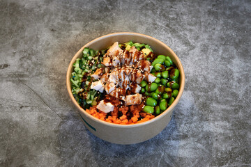A bowl of food with a mix of vegetables and meat. The bowl is brown and has a green label on it