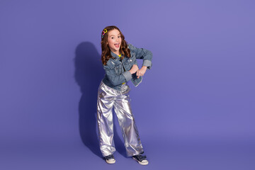 Smiling preteen girl posing confidently in stylish outfit on vibrant purple background
