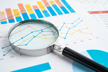 Magnifying glass on spreadsheet and graph paper. Financial data economy, Business.