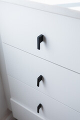 White drawers in modern kitchen with contemporary black handles - stock photo - light, white quartz top and white cabinets