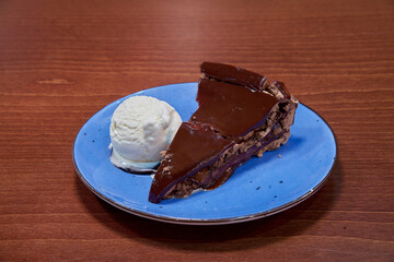 A slice of chocolate cake with ice cream on a blue plate. The cake is cut in half and the ice cream is on the left side