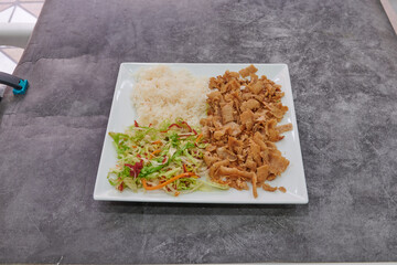 A plate of food with a piece of meat and a salad. The meat is cut into small pieces