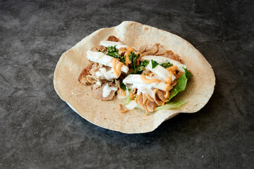 A plate of food with a wrap on it. The wrap is filled with lettuce and cheese. The plate is on a counter
