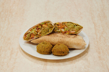 A plate with a wrap and two pieces of food on it. The wrap is open and the food is a mix of vegetables and meat