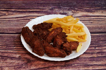 A plate of fried chicken and french fries. The chicken is covered in a brown sauce. The fries are golden brown and crispy
