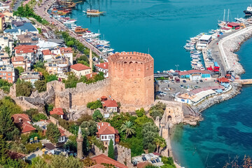 Aerial view of Red Tower (Kizil Kule) in Alanya, Turkey, with historic walls, harbor, boats, and waterfront buildings set against vibrant Mediterranean scenery. Alanya — October 24, 2020