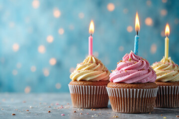 three cupcakes with lit candles on top of them