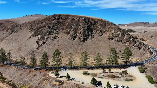 Drone view of a highway around hill in a valley by the hmas hobart shipwreck lookout on a sunny day
