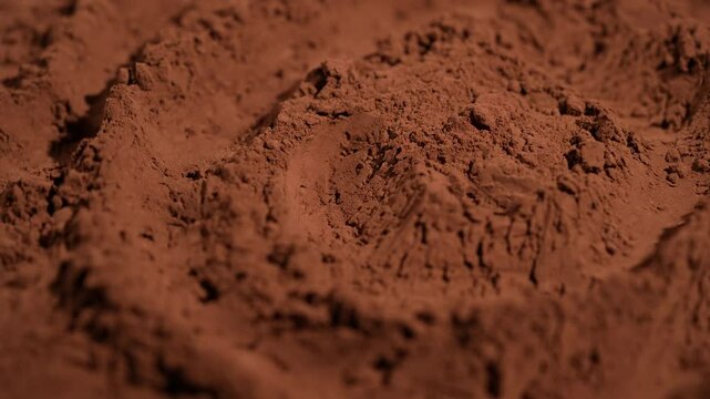 Natural dark brown cocoa powder textured background, close up, rotation. Heap of organic cacao powder