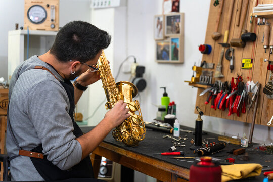 Instrument repairman examining saxophone in workshop