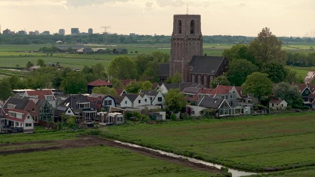 Aerial view of dutch village of Ransdorp with farmland and modern buildings of Amsterdam Noord in the distance
