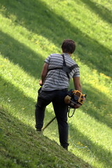A man uses a petrol trimmer to mow grass on a slope near the Ryazan Kremlin