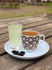 Traditional Turkish coffee served with lemon water and raisins on white saucer over rustic wooden table