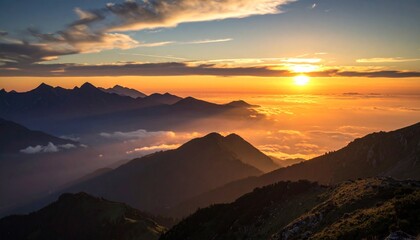 Silhouetted mountain ridge with glowing golden clouds in the background, casting warm light across misty valleys below.