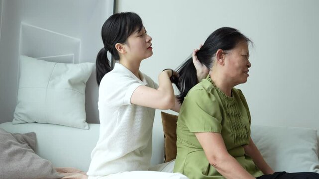 Young Asian woman combing her mother's hair at home
