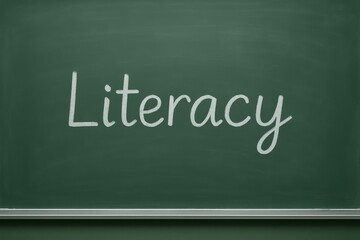 Word literacy written with chalk on green classroom chalkboard symbolizing education, learning, reading and writing skills