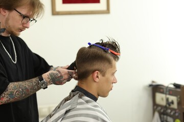 Professional barber making stylish haircut in barbershop
