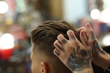 Professional barber working with client in barbershop, closeup