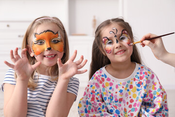 Animator drawing butterfly on girl's face indoors, closeup