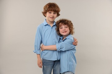 Cute little brothers hugging on light background