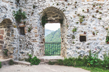 Fototapeta premium Ancient stone fortress in the Karadeniz mountains of Turkey. Through the arched doorway, lush green hills stretch into the distance, framed by the weathered, plant-covered walls. travel concept