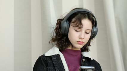 A young girl wearing headphones leans back with a confident expression, enjoying the moment. This...