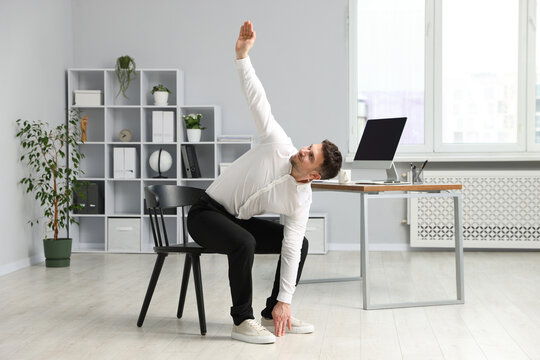Handsome man stretching on chair in office