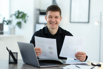 Handsome man working with documents at desk in office